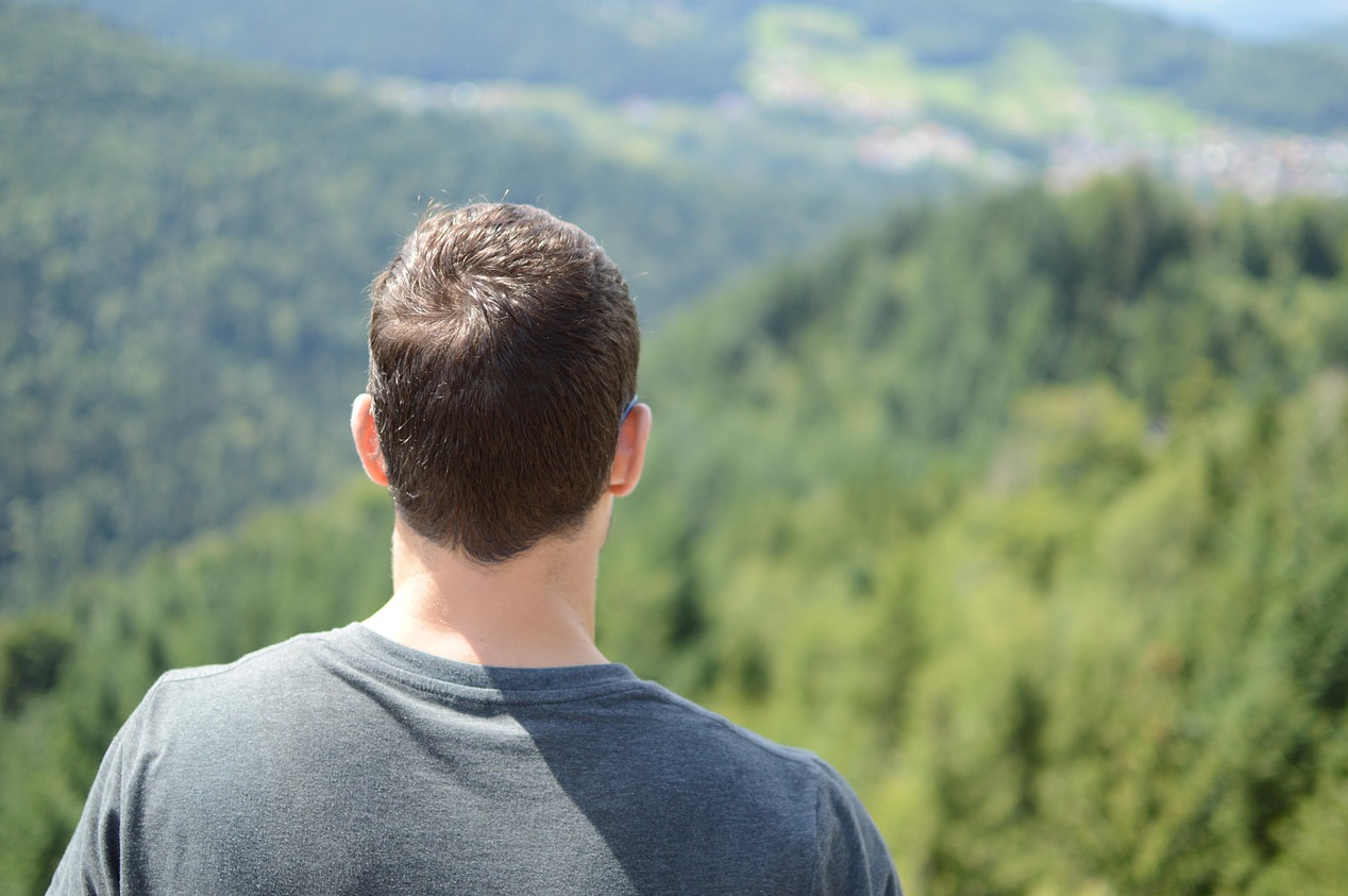 한 남성이 산 위에서 맞은 편 산을 바라보고 있다