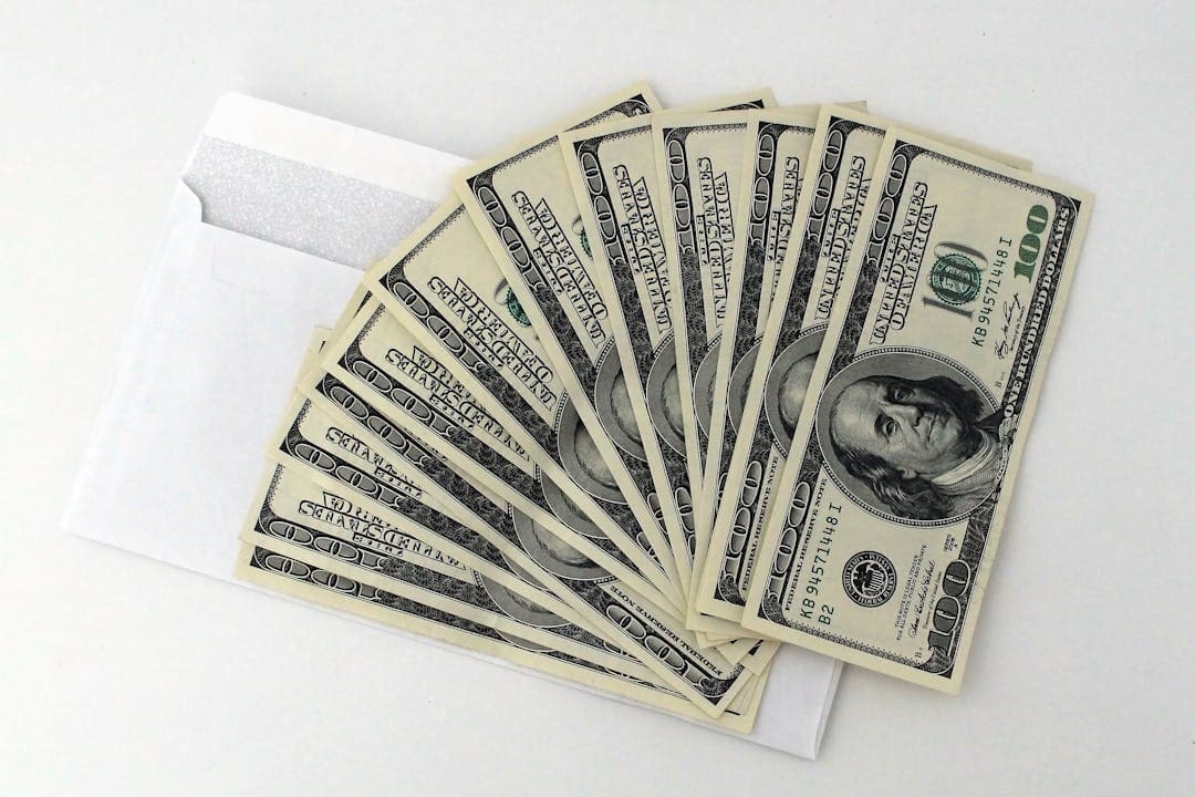 흰 봉투에서 펼쳐진 달러 지폐 이미지