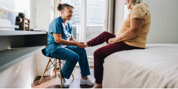 노인의 발을 만저주고 있는 보호사의 사진