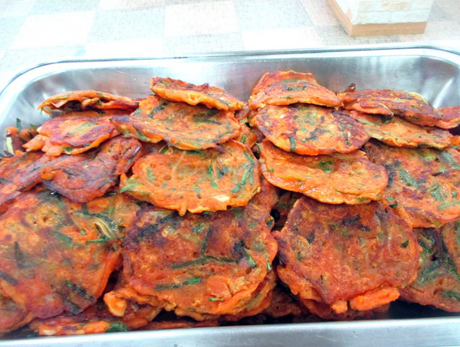 쇠로 된 네모난 그릇에 고추장과 밀가루를 섞어서 부치고, 부추와 고추를 넣어 장식을 한 고추장떡을 수북하게 쌓아두고 찍은 사진