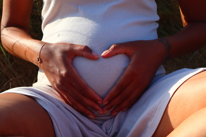 임산부가 배 위에 손을 올려 하트 모양을 만들고 있는 모습