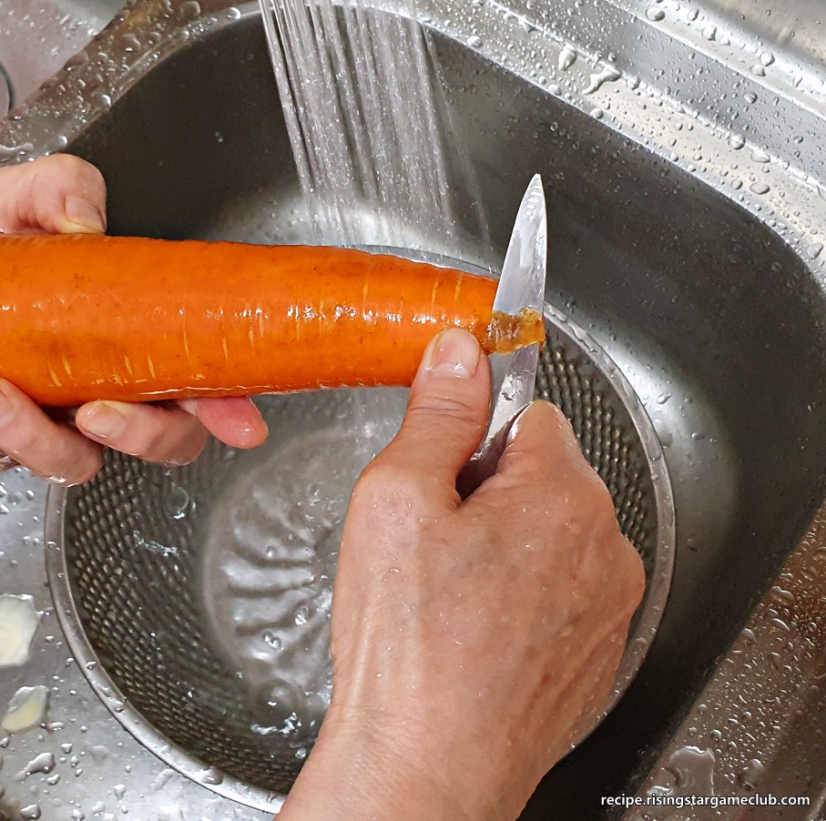 돼지고기 카레라이스에 들어갈 당근을 깨끗이 씻어서 검은 부분을 깎아서 제거하는 사진
