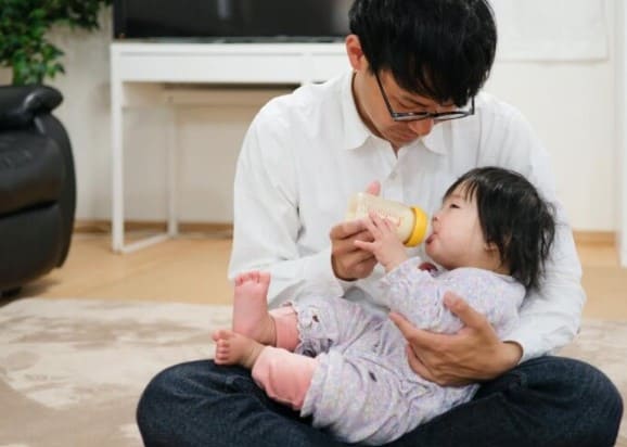 남성이 아기를 안고 분유를 먹이고 있는 사진