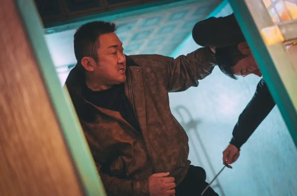 범죄도시-갈색옷을 입은 마동석이 화장실안에서 칼을 든 상대와 싸우고 있는 모습