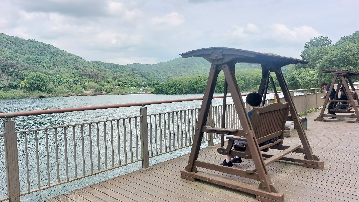 나무 그네에 앉아 호수를 바라보는 사람들