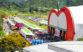 장수 한우랑 사과랑 축제 행사장 전경&amp;#44; 사과 모양 건물과 행사장을 가득 채운 관람객 모습