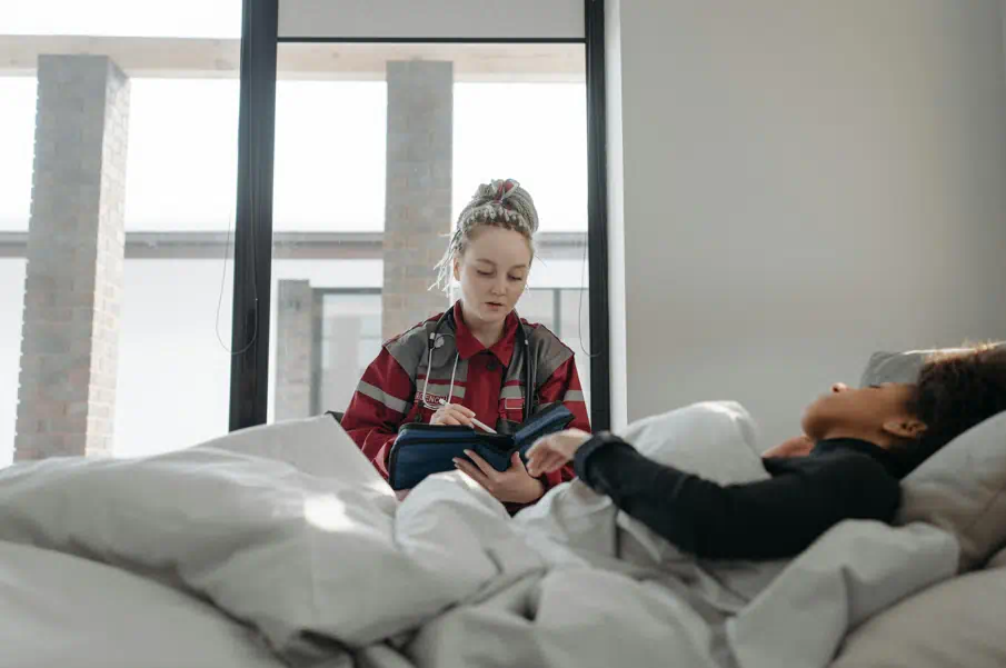 한 남성이 누워있고 한 여성이 그를 건강검진을 해주고 있다