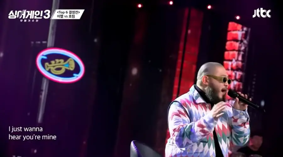 싱어게인3-
검은배경 보라색 빨강색 격자무늬 외투 검은색 폴라티에 검은 선글라스 검은 마이크에 노래하는 16호 오른쪽 모습