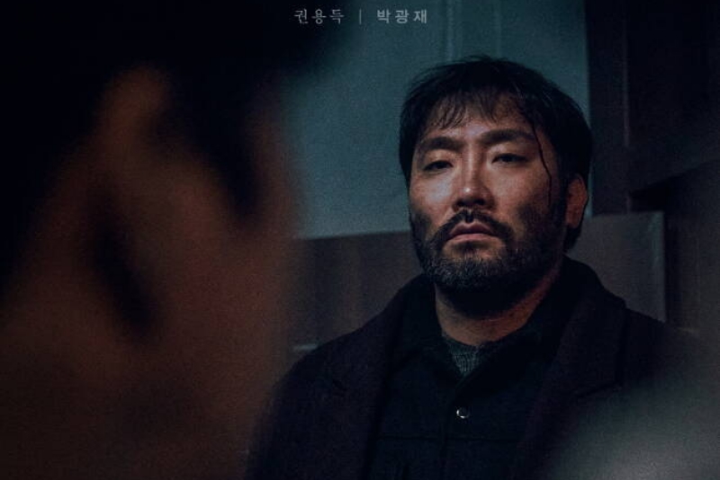 학교 교사실을 배경으로 갈색 긴 코트에 턱수염이 거칠게 난 덩치 큰 드라마 무빙의 북파 공작원 권용득 캐릭터