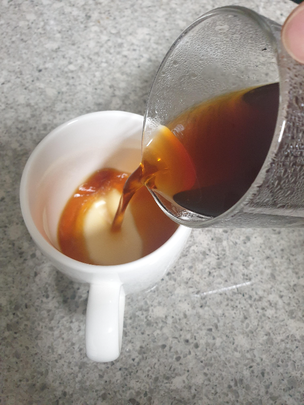 테이블 위에 있는 컵에 추출된 커피를 붓는 모습