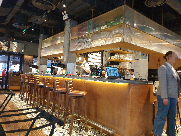 우드 바 테이블 너머 오픈형 키친이 보인다.