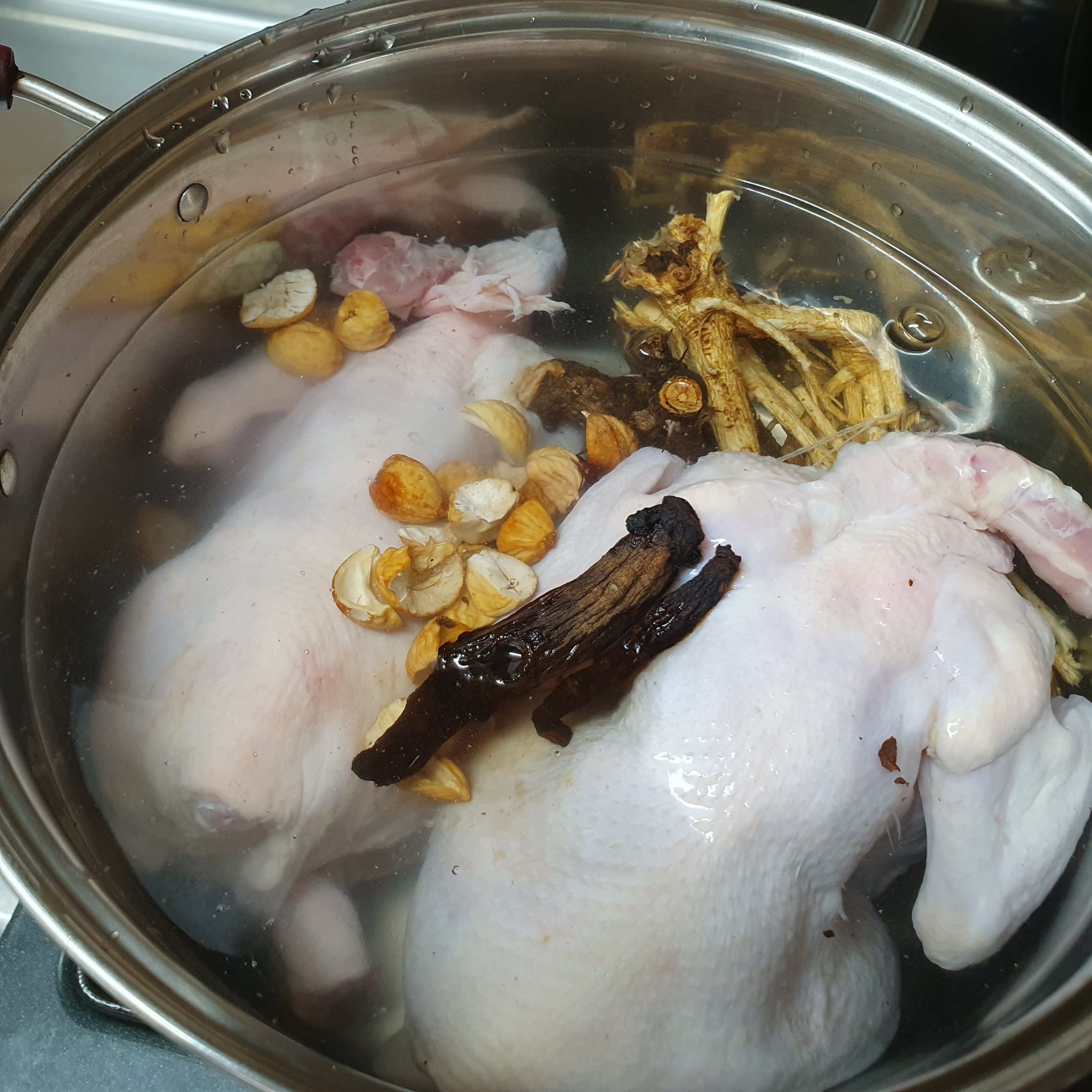 큰 냄비에 물을 붓고 닭과 삼계탕을 끓일 재료들을 넣은 사진