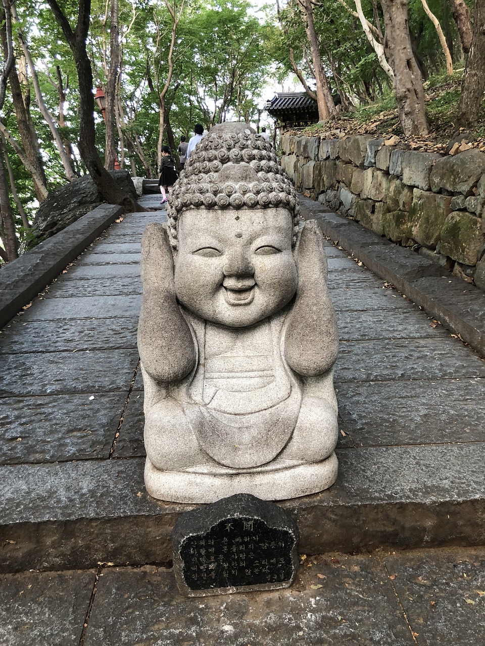 a statue of a small monk covering his ears and smiling