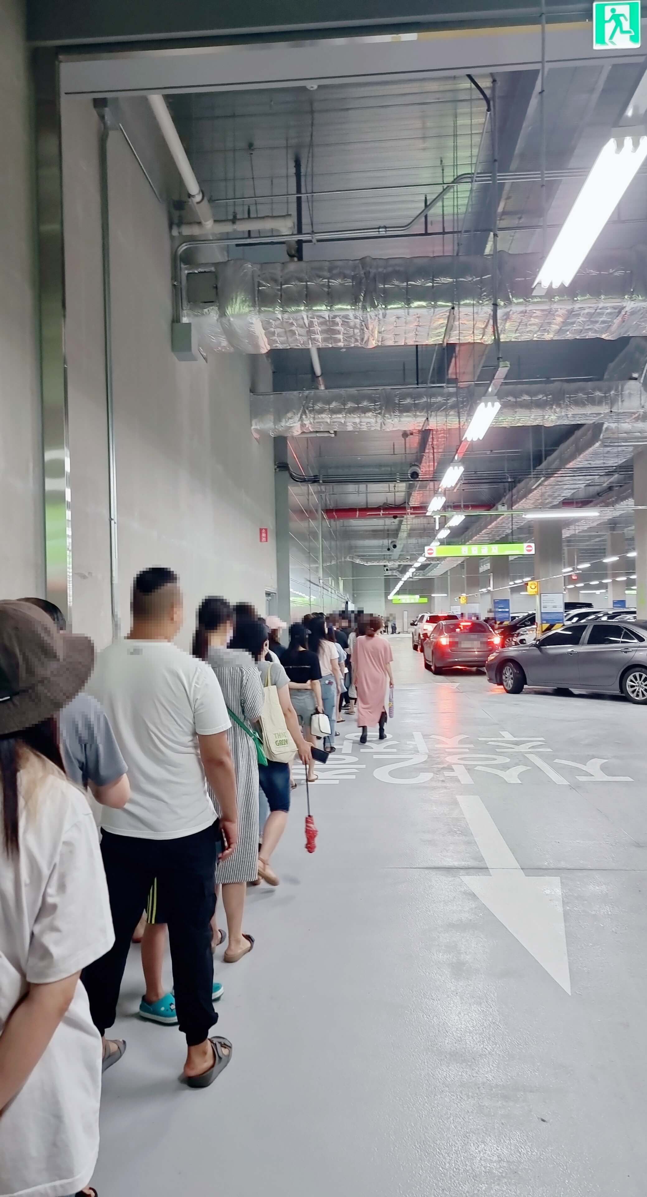 주차장에 한줄로 대기하고 있는 번호표 반는 사람들