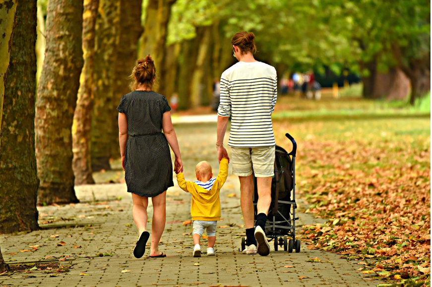 아이의 손을 잡고 평화로운 공원을 걷고 있는 부부의 모습