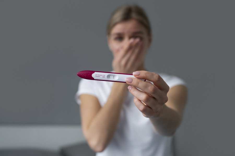 젊은 서양 여성이 임신테스트기를 통해서 임신 여부를 검사를 했는데 1줄이 나와 있는 임신테스트기를 보여주면서 임신이 되지 않았음을 알고 실망하고 있는 사진