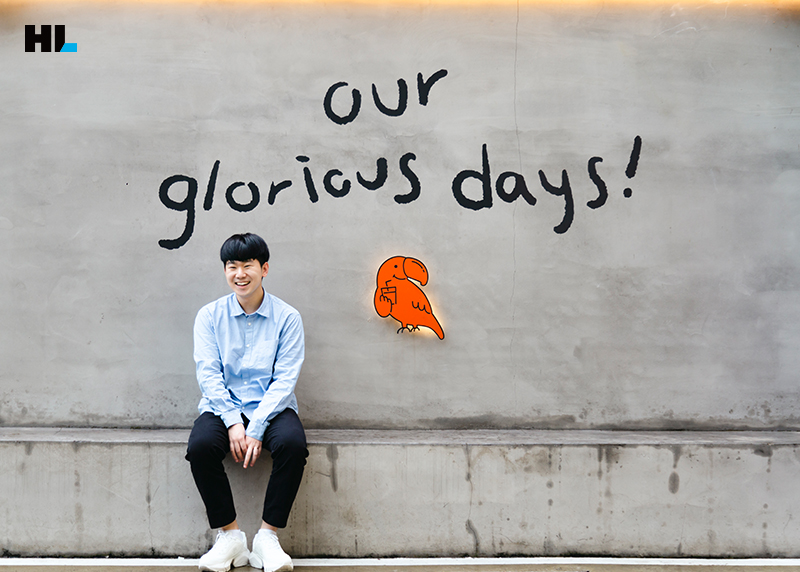 회색 콘크리트 벽 앞에서 포즈를 취한 채 앉아 있는 지영민 프로의 모습