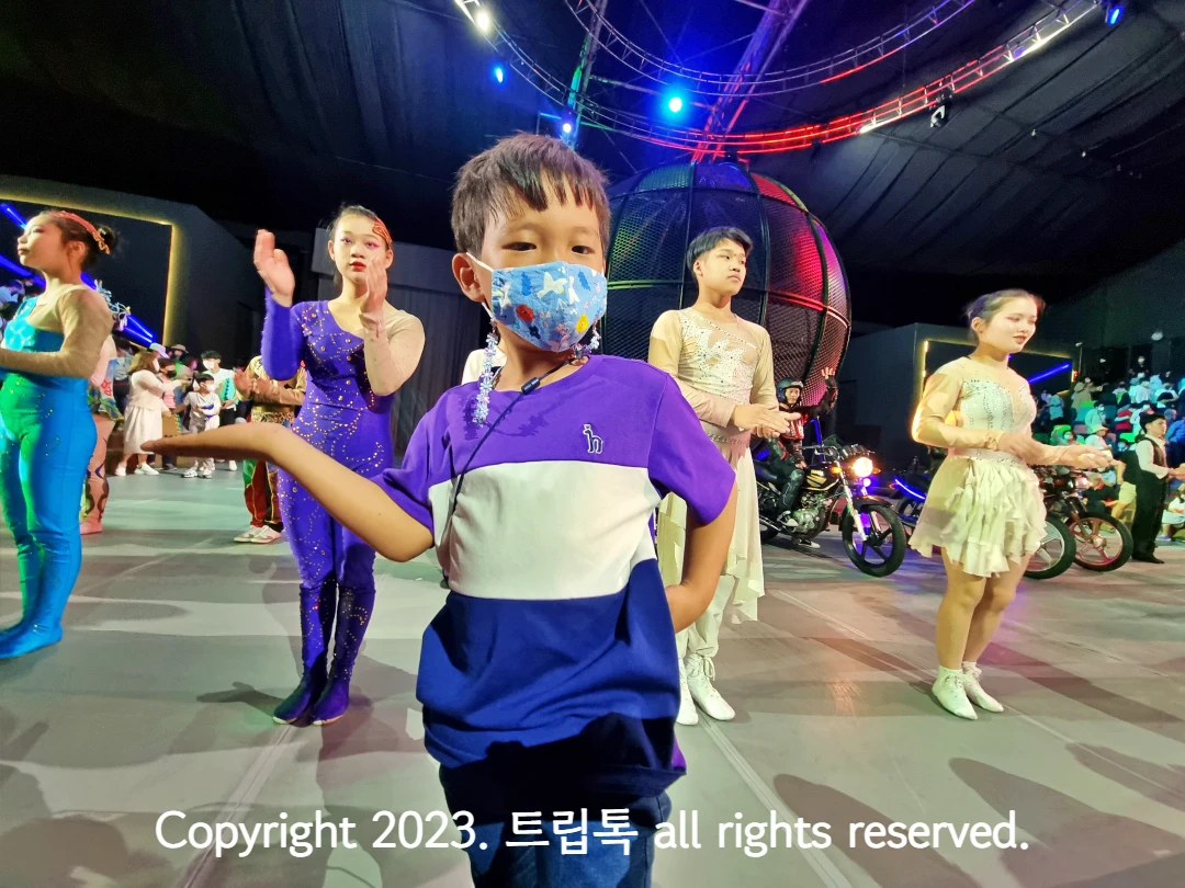 공연자를 배경으로 한 아이가 손을 들고 있다