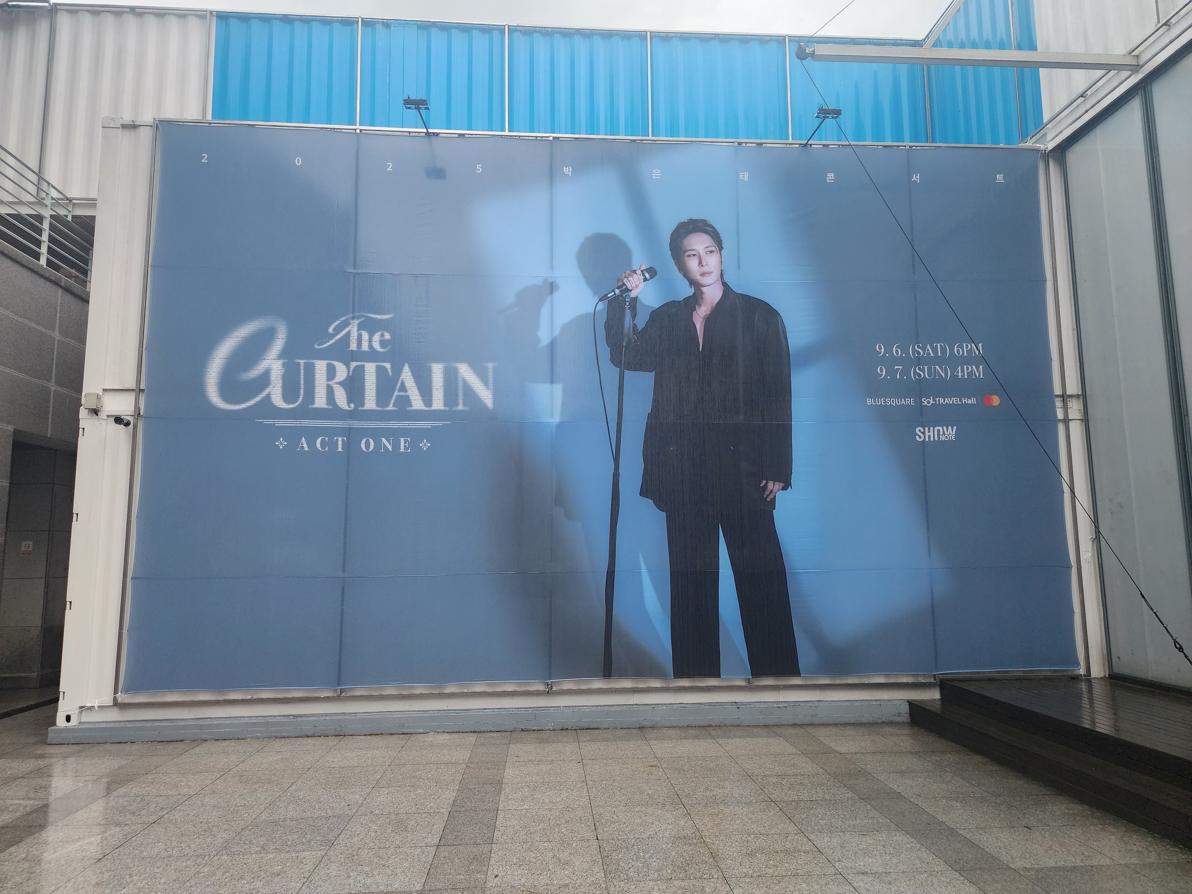2025년 9월 6일 2025 박은태 콘서트 〈The Curtain : Act One〉현장 현수막 공연 포스터 가로형 스탠딩 마이크를 오른손으로 잡고 있는 박은태 배우의 전신 사진