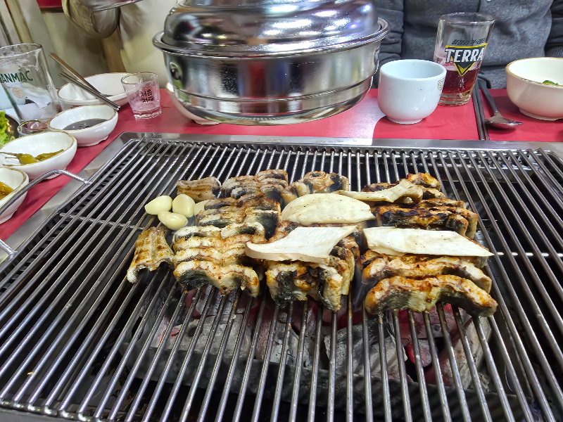 장어가 잘라졌고, 구워지고 있다. 테이블 위다.