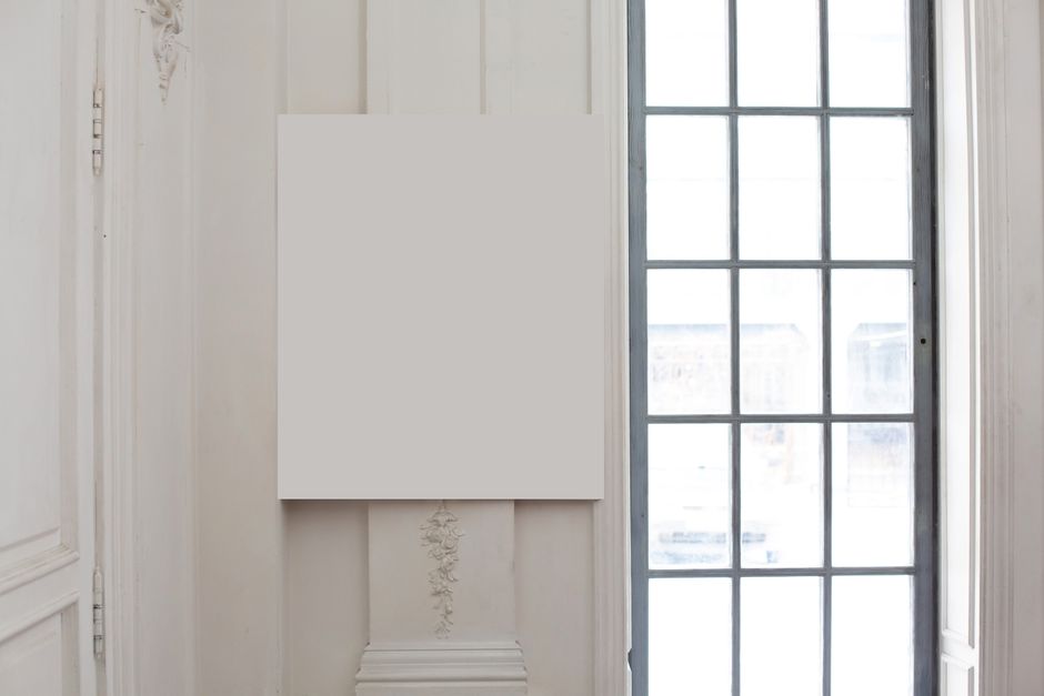 White mock up poster hanging on wall with post and ornamental elements near big window in light room in studio