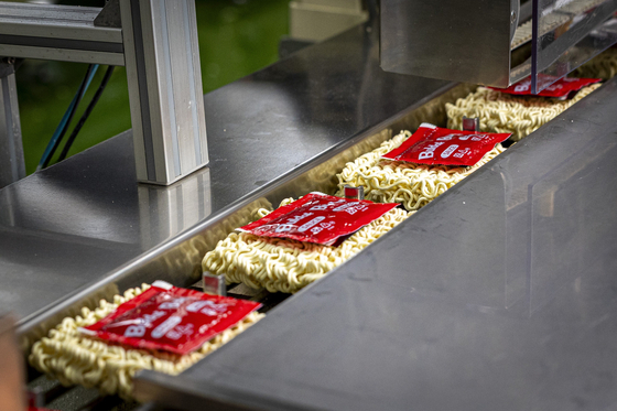 삼양식품 밀양 제1공장에서 불닭볶음면 제품이 포장된 소스와 함께 컨베이어 벨트를 따라 운반되고 있다.
