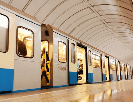 실내 지하철이 길게 정차해있다. 안에는 사람들이 앉아있다.