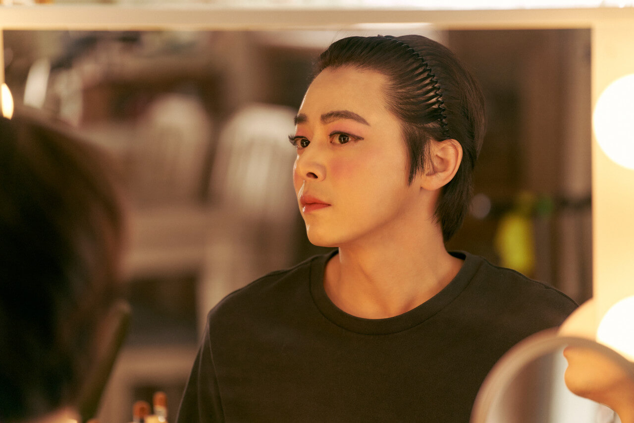 한정우가 거울앞에서 여장한 자신의 모습을 쳐다보고 있는 모습