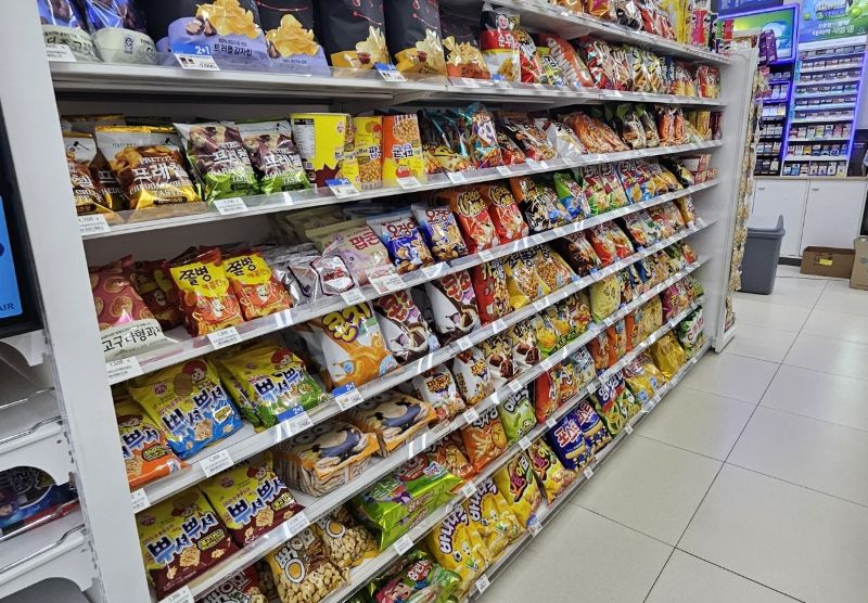 명절 연휴가 끝난 후 카페나 편의점 매장에서 명절 홍보물을 제거하고 진열대를 청소하는 사장의 모습. 깨끗하게 정돈된 매장 전경을 통해 빠른 정상화를 보여주는 이미지.