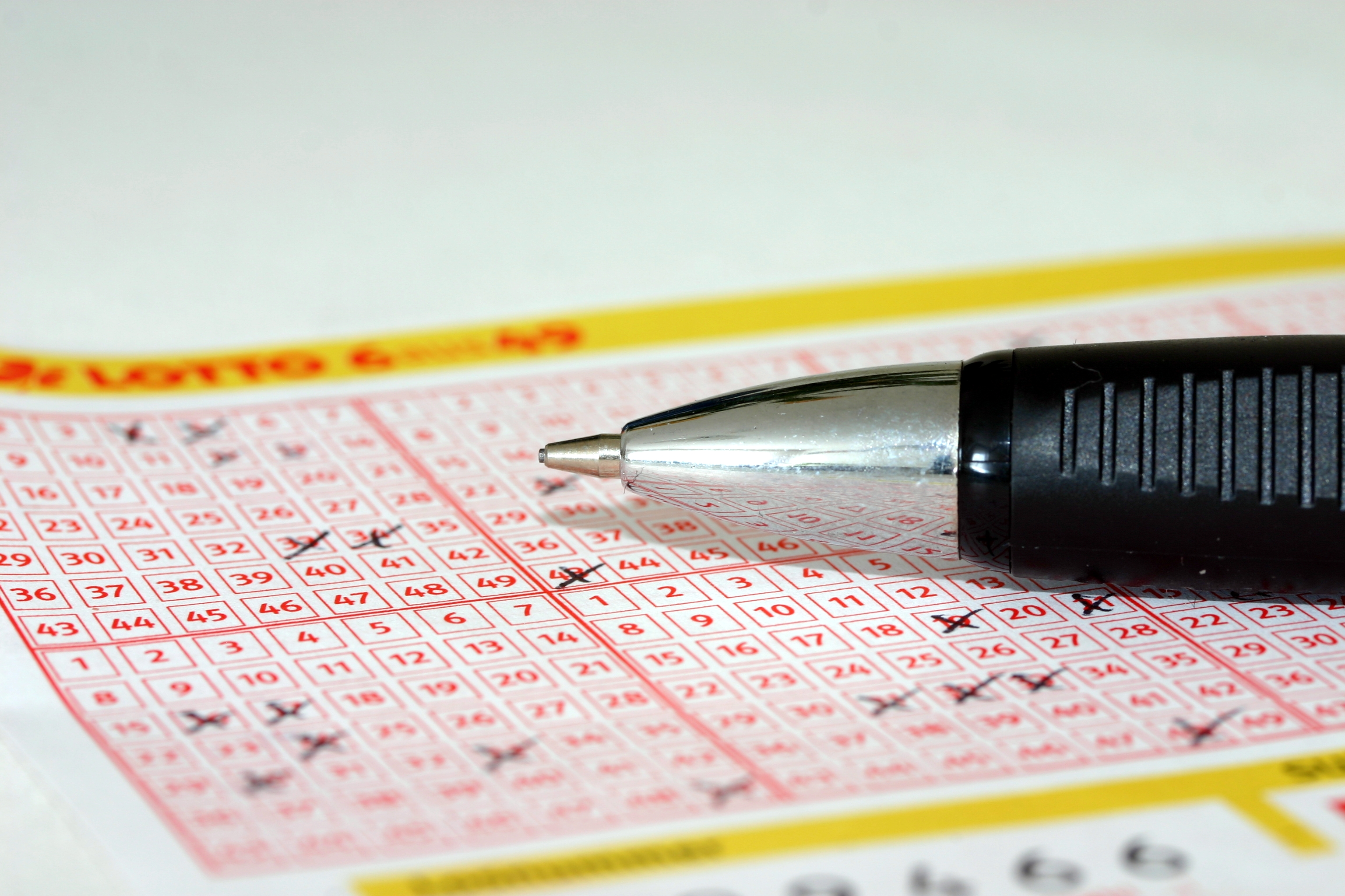 로또 복권 번호 용지에 번호를 체크하며 볼펜으로 선택하는 모습, 당첨을 기대하는 장면