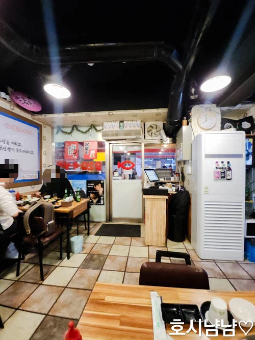 하남 920숙성회 내부 분위기 - 따뜻한 조명 아래 테이블과 입구가 보이는 실내 전경