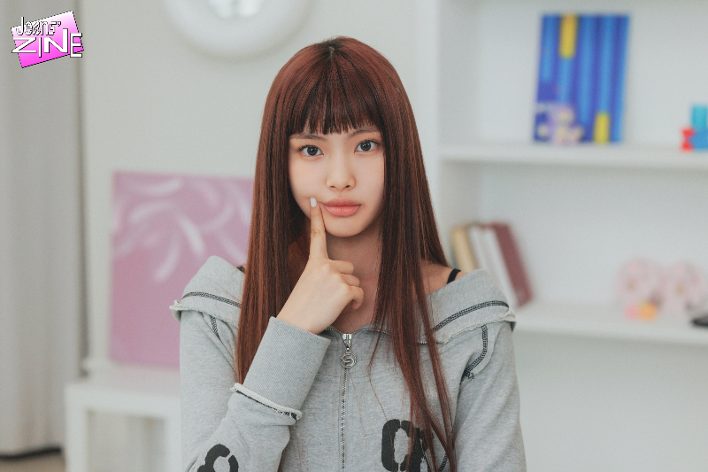 뉴진스-멤버-혜인이-정면을-보며-오른손-검지로-한쪽-입술을-올리는-포즈를-취하고-있다