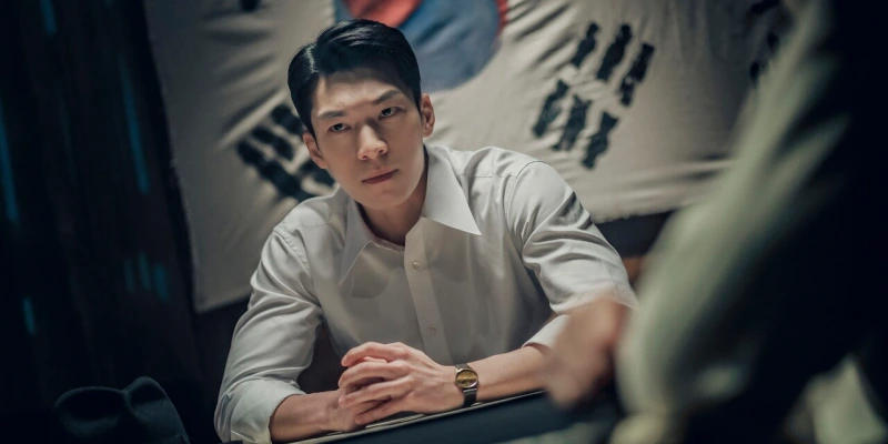 태극기를 배경으로 흰 와이셔츠를 입고 앉아 있는 경성크리츠의 위하준