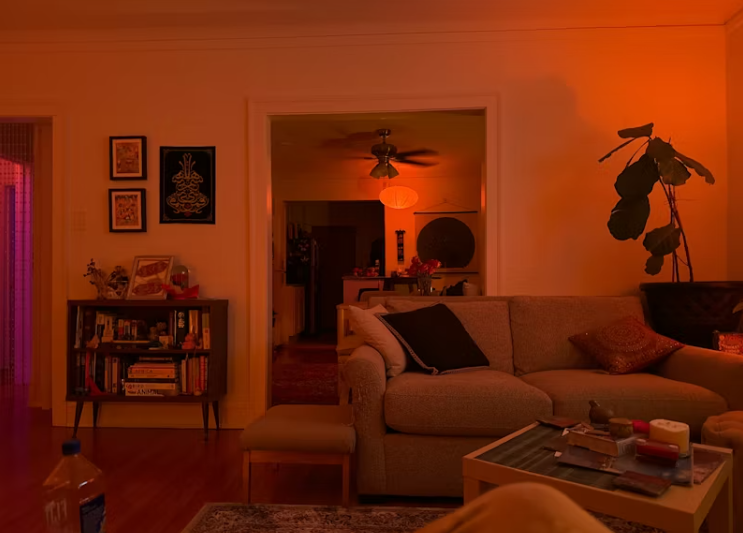 따뜻한 조명 아래 정리된 거실 공간, 소파와 테이블, 식물 등이 놓여 있어 편안하고 안정적인 분위기