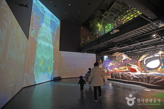 건물내부에 동물모형과 대형 스크린이있으며 엄마와 아이가 구경하고 있다