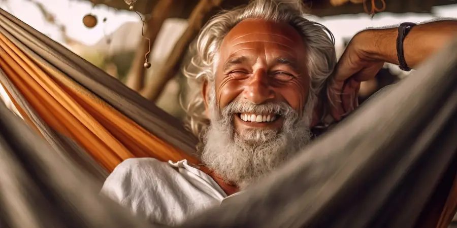 고용지원금- 주황색 흔들 해먹에 누어 화면을 보고 웃고있는 머리가 하얗고 흰수염을 한 할아버지