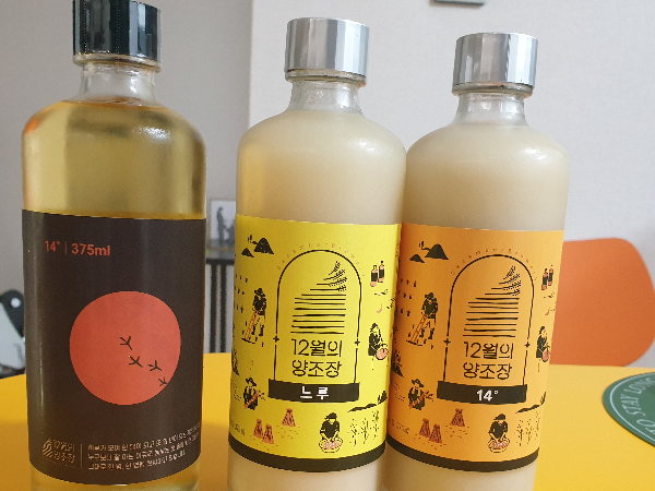 노란 테이블 위에 약주 한 병과 탁주 두 병이 보인다.