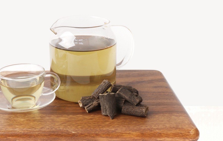 야생에서 채취를 한 오가피를 하얀 바닥 위에 갈색의 네모난 도마 위에 한움큼 놓아두고 그 옆에는 투명한 주전자와 찻잔에 오가리를 넣고 끓인 오가피차를 가득 담아두고 찍은 사진