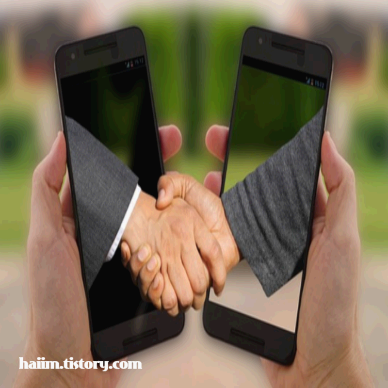 두 개의 스마트폰 화면을 통해 손이 뻗어나와 악수하는 모습. 비대면 시대의 온라인 협력과 디지털 소통을 상징하는 이미지.