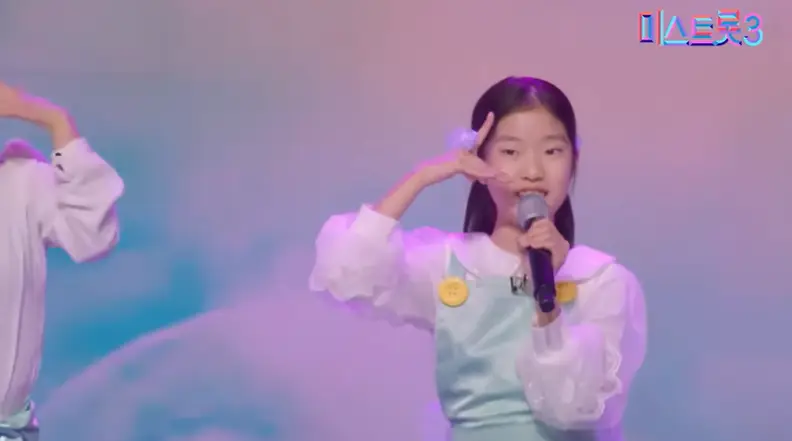 미스트롯3- 파란배경 앞 파란드레스를 입고 왼손에 마이크를 든채 귀엾게 노래하는 빈예서