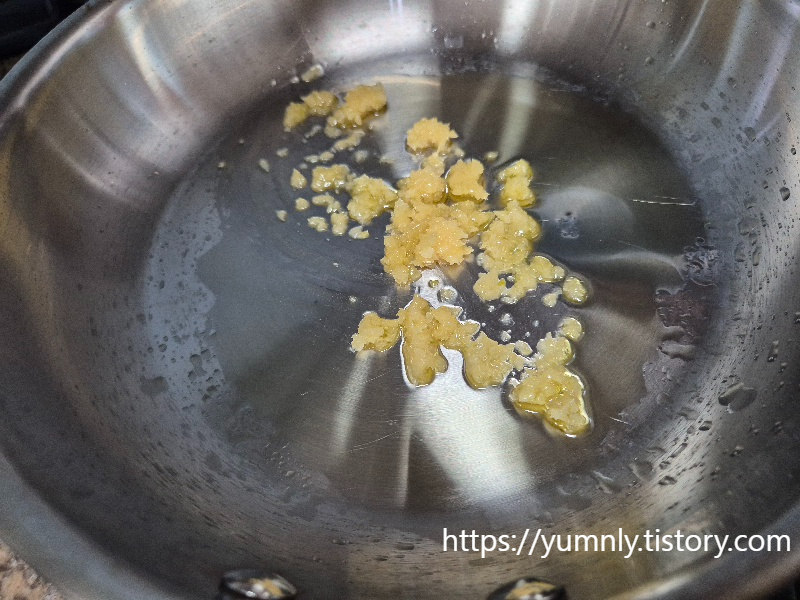 Saut&eacute;ing minced garlic in a frying pan on a stovetop