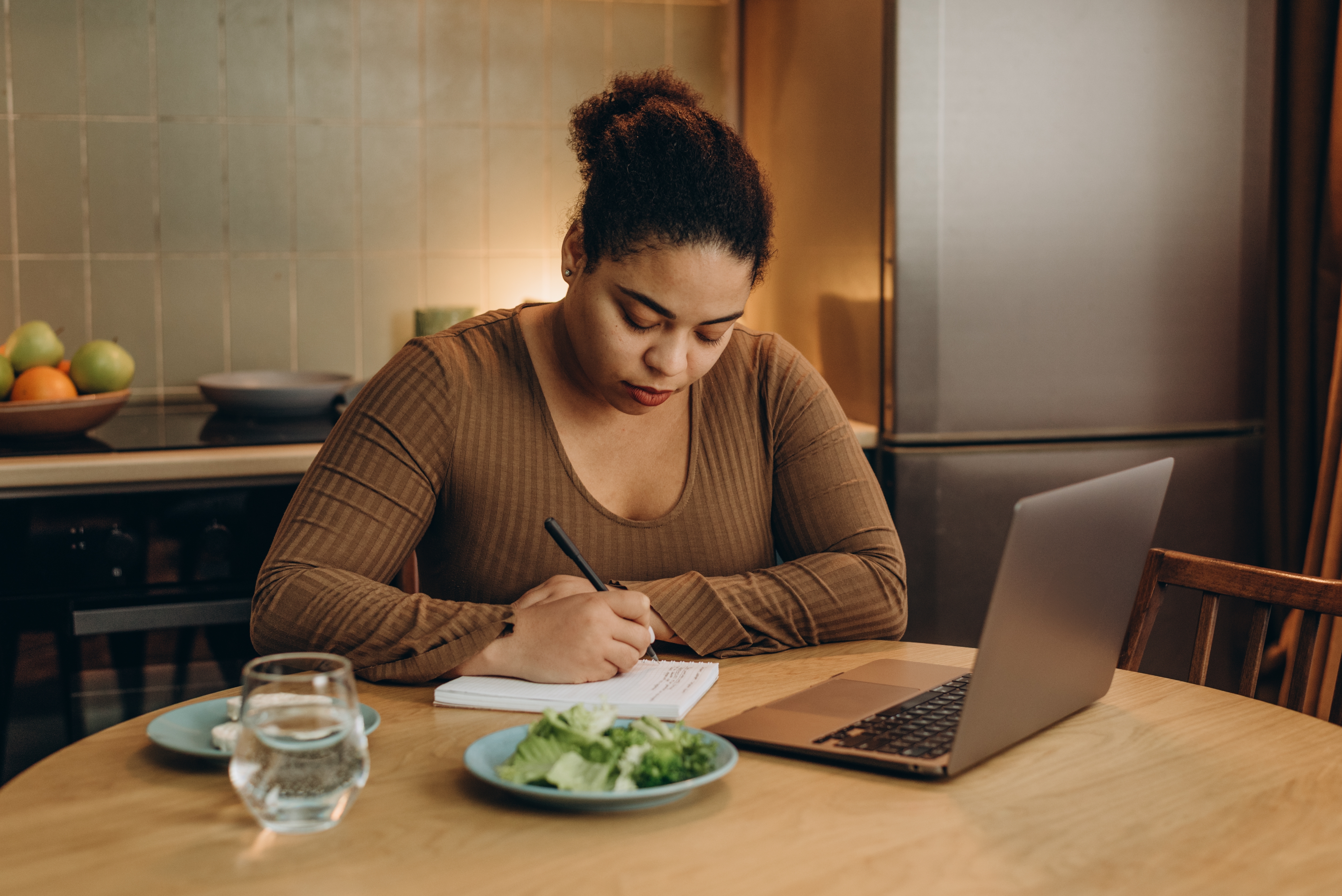다이어트 식사와 함께 다이어리 작성에 집중하는 여성 – 실천 루틴 기록을 통해 작심삼일을 극복하는 모습