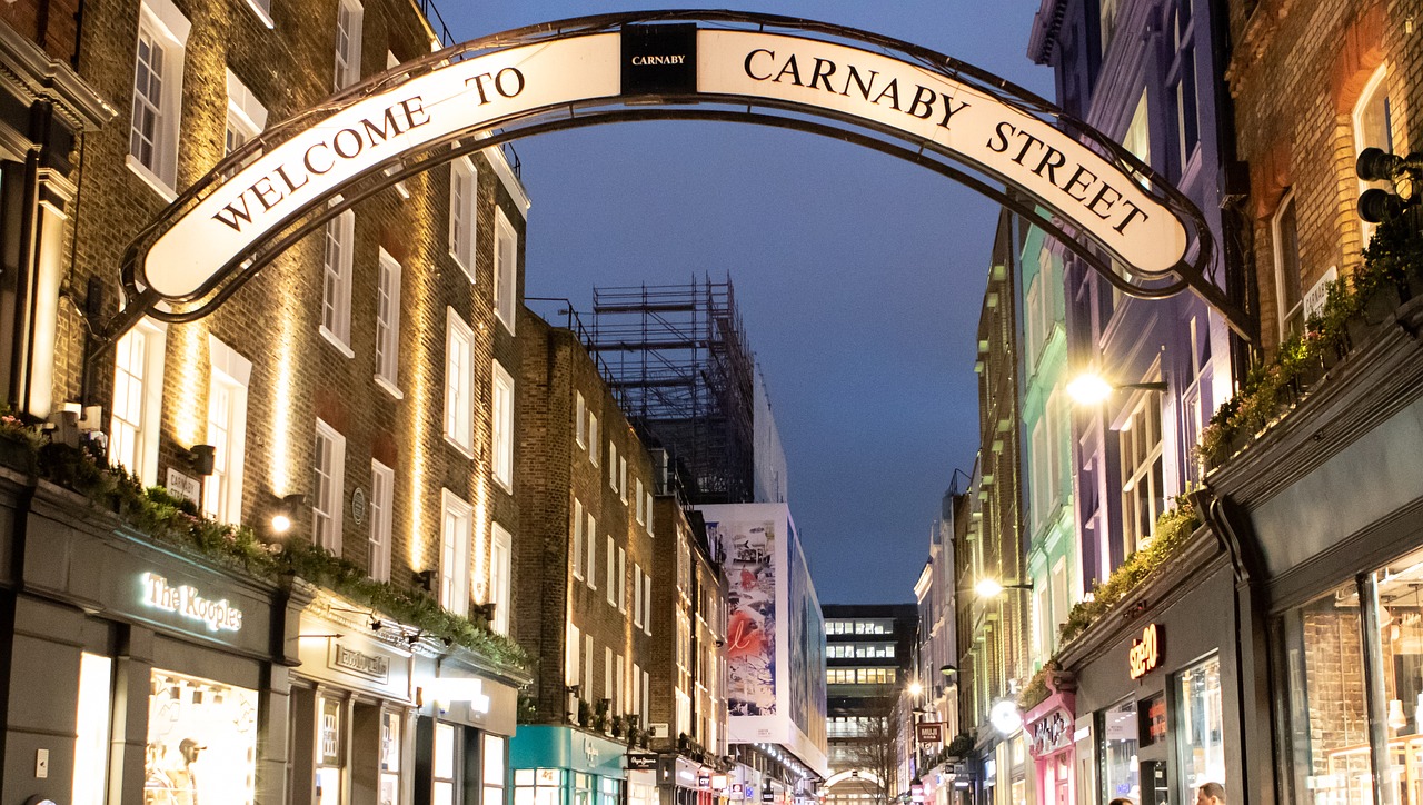 카나비 스트리트의 야경 풍경. 거리 입구에 “Welcome to Carnaby Street” 아치형 간판이 설치되어 있으며, 양 옆으로 조명이 비친 상점들과 거리 모습이 담겨 있다