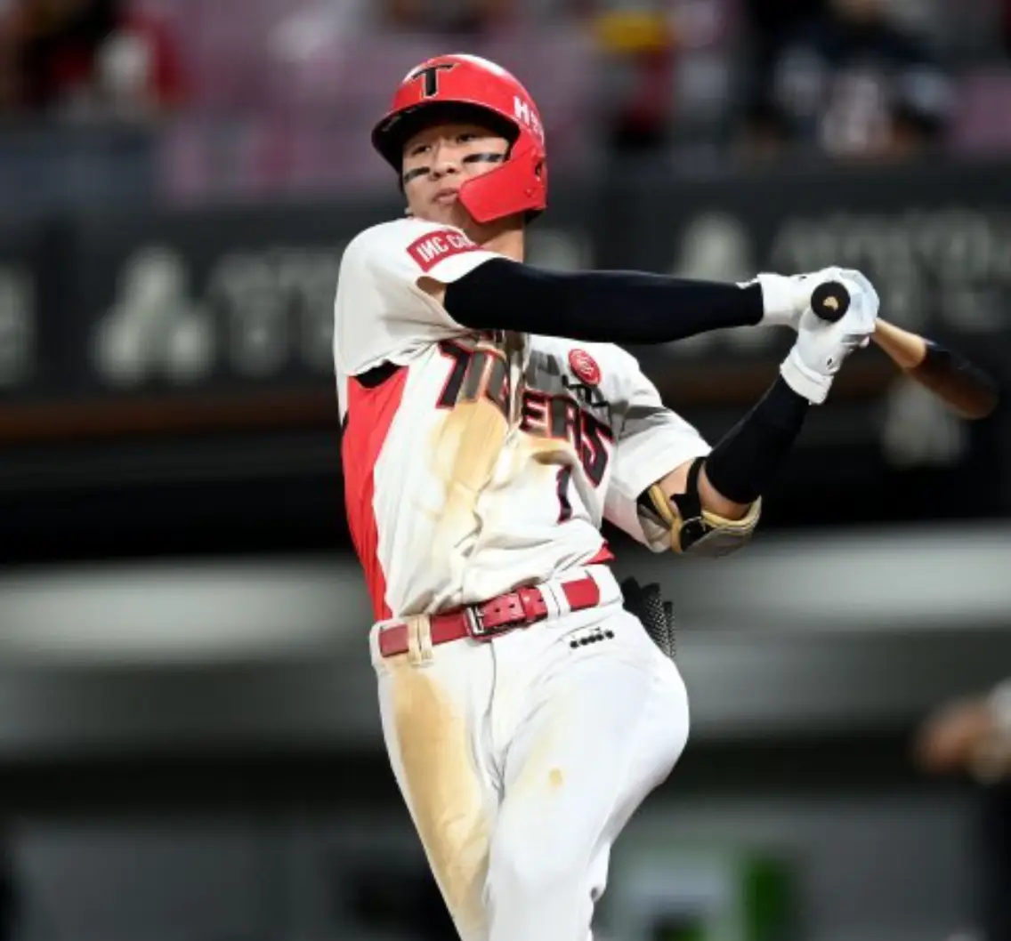 붉은 헬맷 흰색 기아타이거즈 유니폼을 입고 두손으로 나무배트를 휘두르고 있는 박찬호