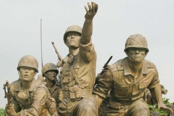 군복입은 남자 넷 동상. 한 군인은 손에 총을 한군인은 칼을 어깨에 메고 전진 자세를 취하고 있다.