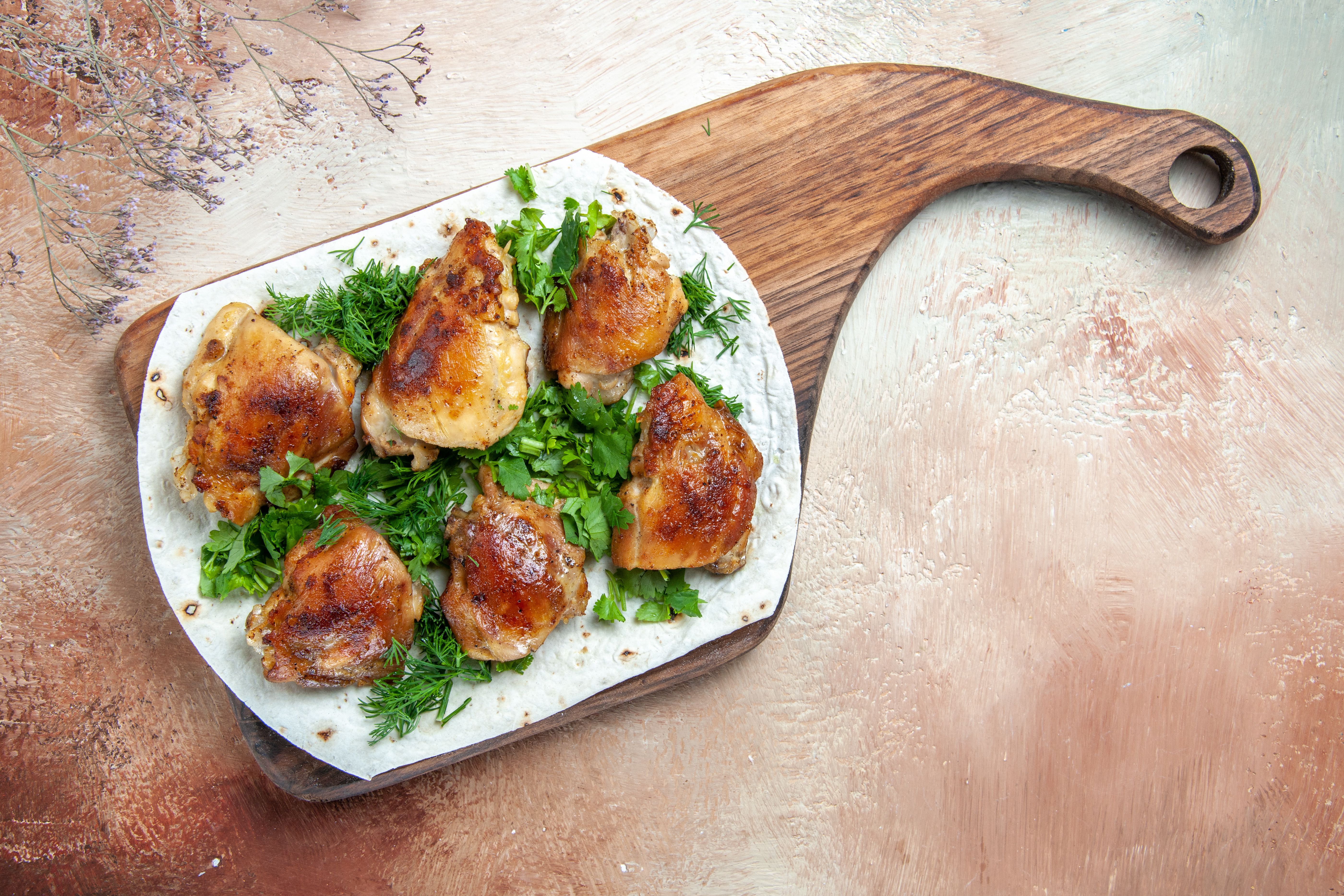 고동색 바닥에 나무 쟁반을 놓고, 하얀 그릇 위에 닭고기를 토막내서 튀긴 닭튀김을 6개 놓고, 각종 야채를 잘라서 뿌려 놓고 위에서 찍은 사진