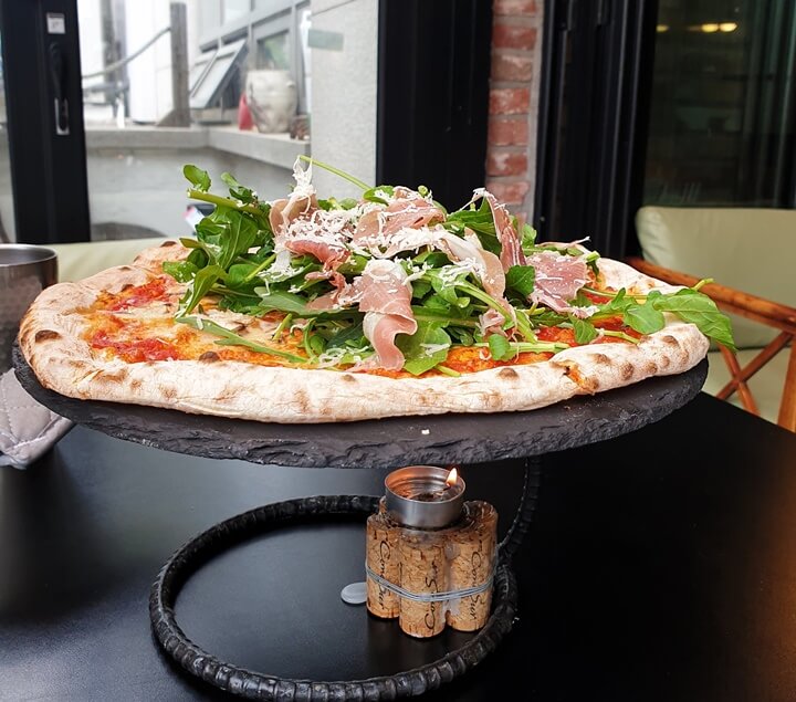 프로슈토루꼴라피자-아래에-따뜻하게-먹을수있도록-작은초가-피자를-데피고있다