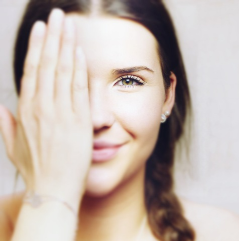 한 손으로 얼굴의 반을 가리고 미소짓고 있는 여자