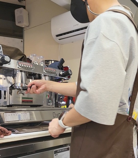 카페 유니폼과 앞치마를 착용한 사장의 뒷모습