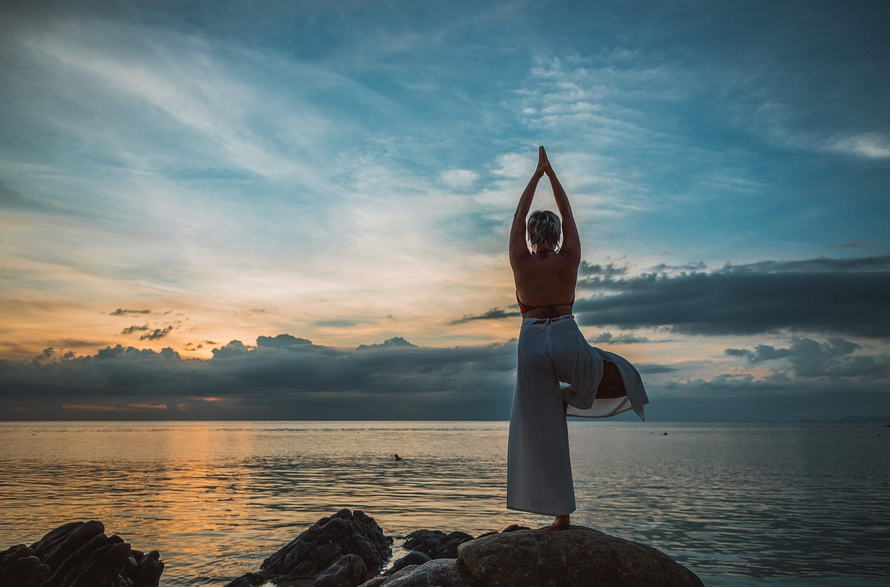 한 여성이 바닷가에서 손과 다리를 올리고 스트레칭을 하고 있다